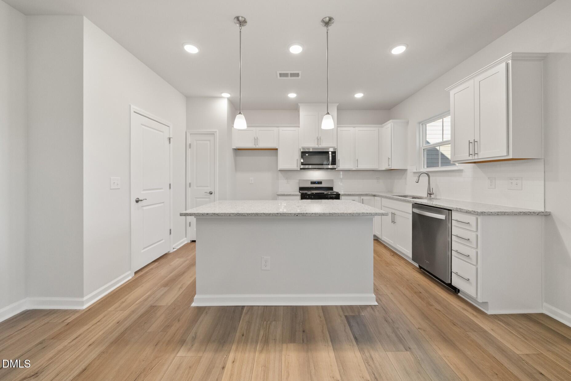 213 Bridle Brk Way Fuquay-Varina, NC 27526 - Photo 3 of 25 a kitchen with kitchen island a sink a stove a refrigerator and white cabinets
