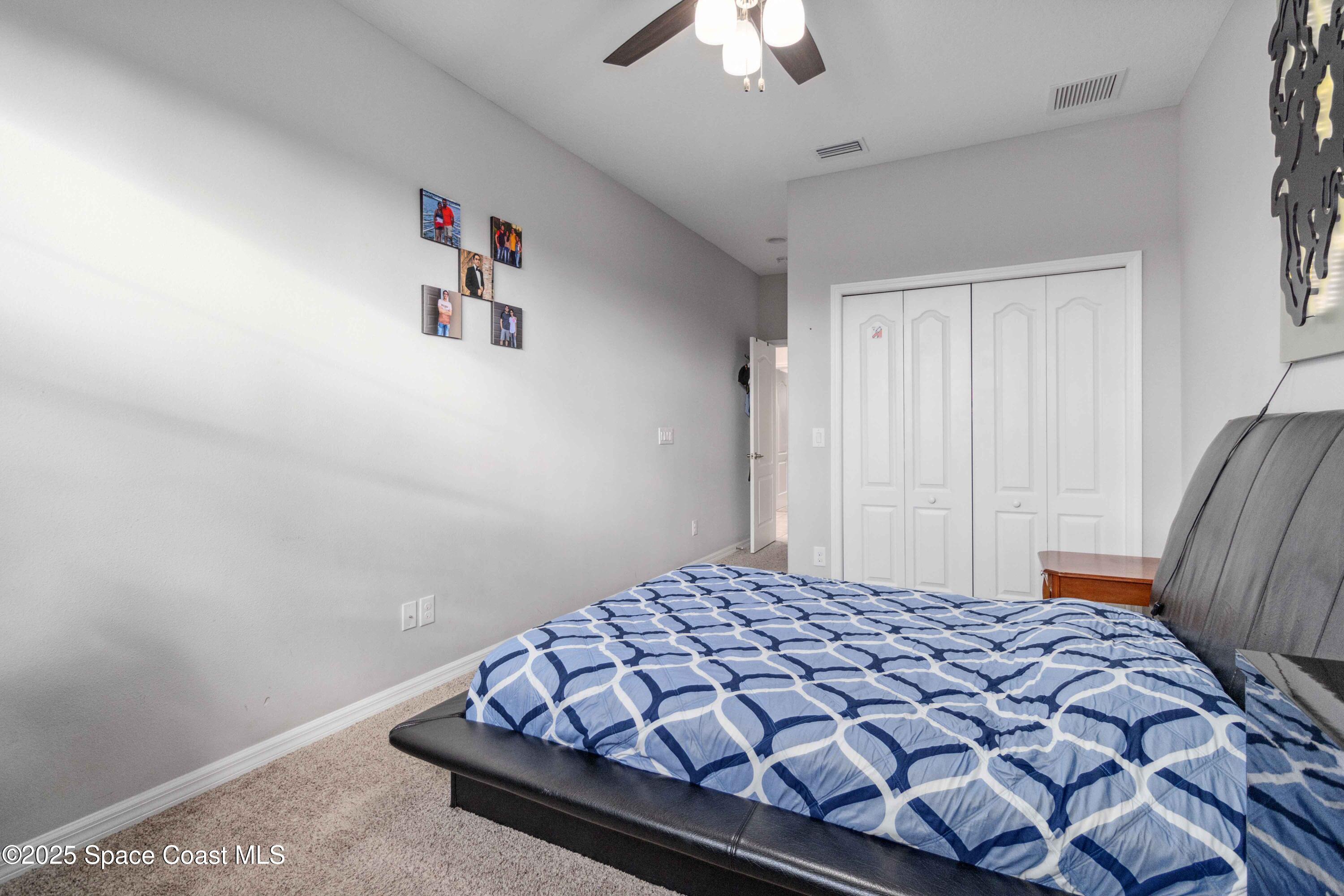 7565 Millbrook Avenue Melbourne, FL 32940 - Photo 18 of 47 a bedroom with a bed and a chandelier