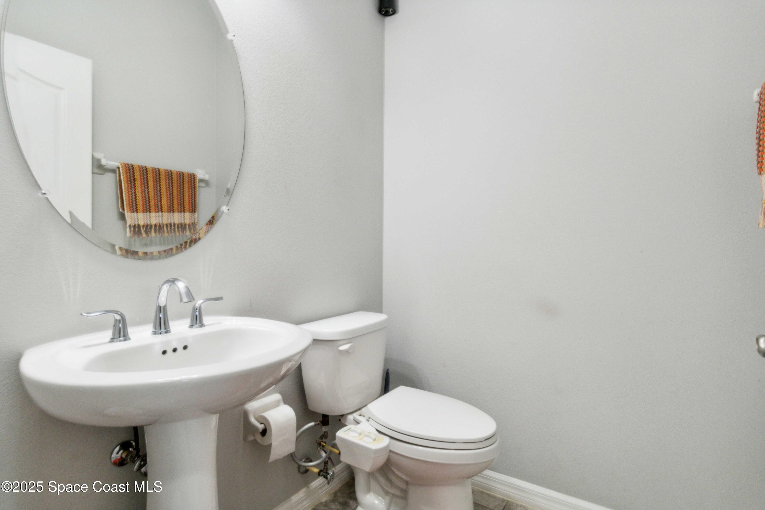 7565 Millbrook Avenue Melbourne, FL 32940 - Photo 23 of 47 a bathroom with a toilet sink and mirror