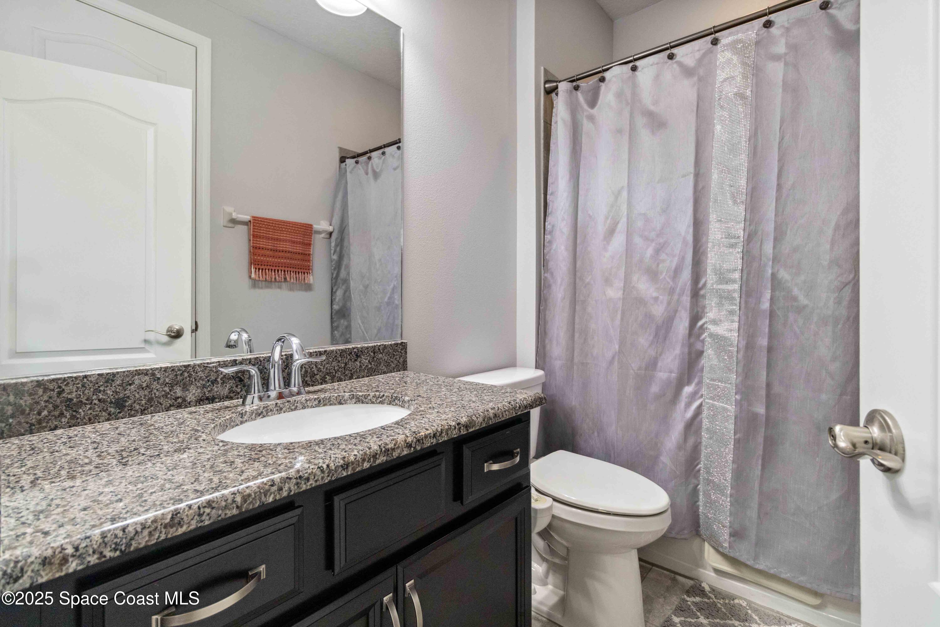 7565 Millbrook Avenue Melbourne, FL 32940 - Photo 26 of 47 a bathroom with a granite countertop sink toilet and shower