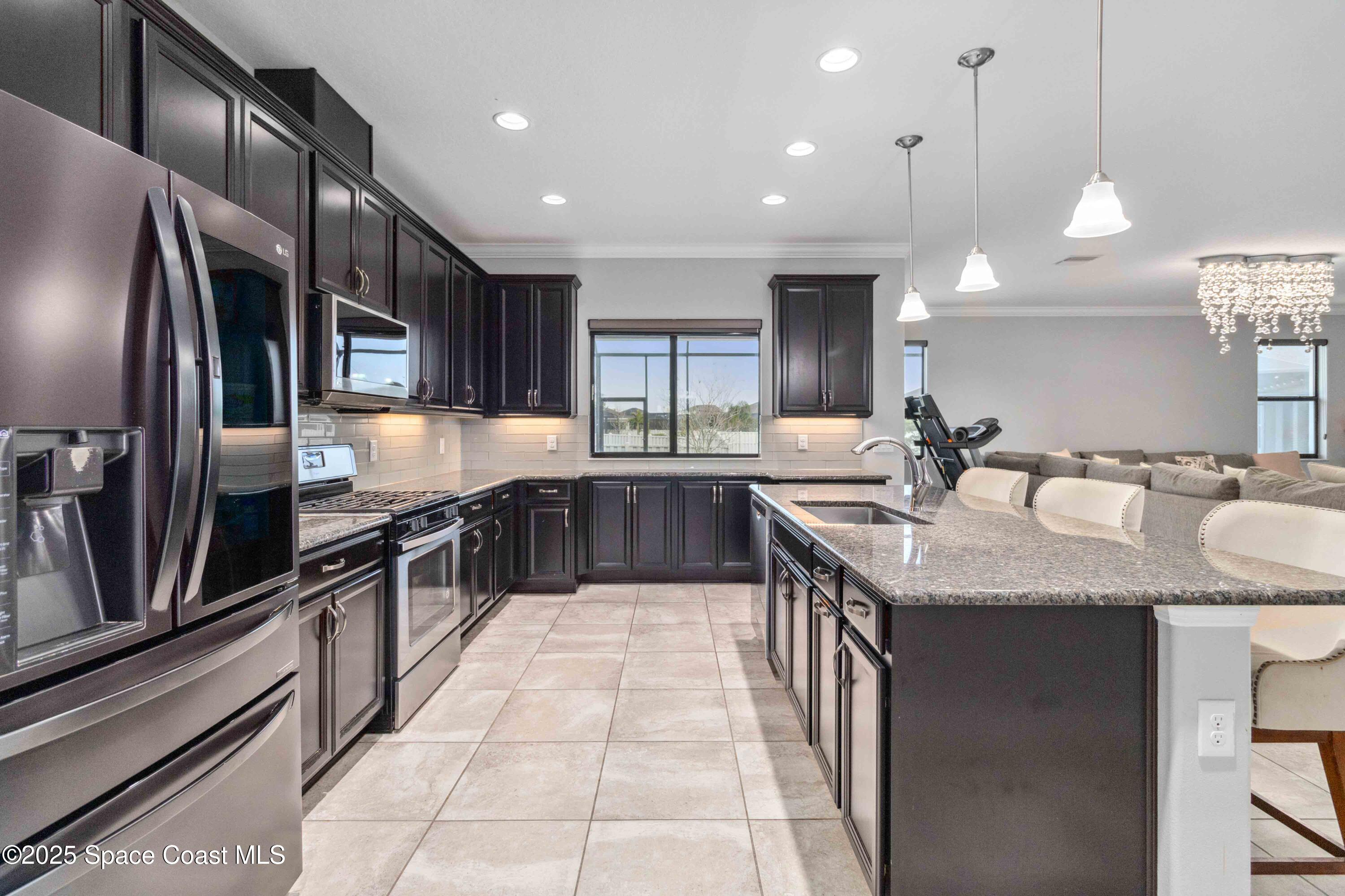 7565 Millbrook Avenue Melbourne, FL 32940 - Photo 9 of 47 a kitchen with stainless steel appliances granite countertop a sink a stove and a refrigerator