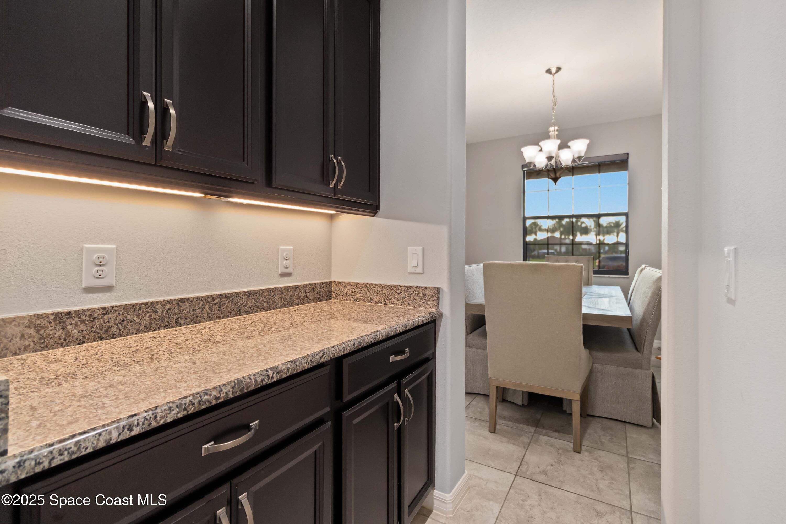 7565 Millbrook Avenue Melbourne, FL 32940 - Photo 10 of 47 a room with granite countertop cabinets and chair