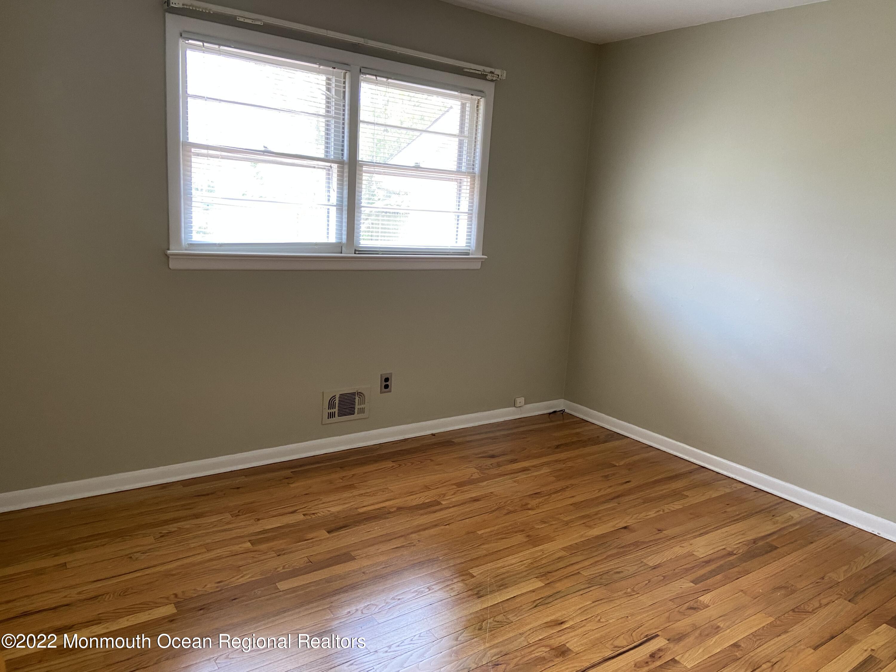 605 Adamston Road Brick, NJ 08723 - Photo 8 of 16 an empty room with wooden floor and windows