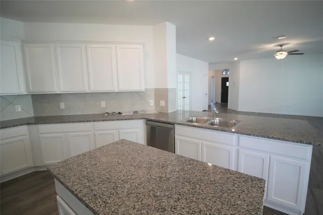 a kitchen with granite countertop a sink stainless steel appliances and white cabinets
