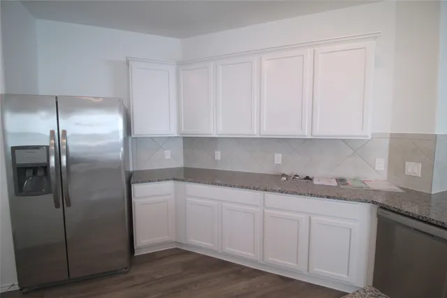 a kitchen with stainless steel appliances granite countertop a refrigerator sink and white cabinets