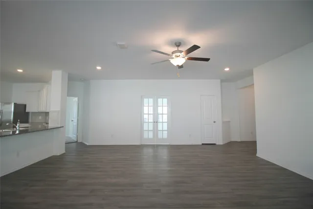 an empty room with wooden floor and kitchen view
