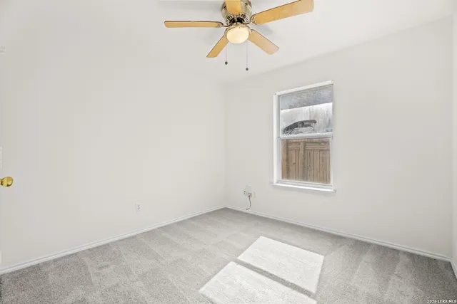 an empty room with chandelier fan and windows