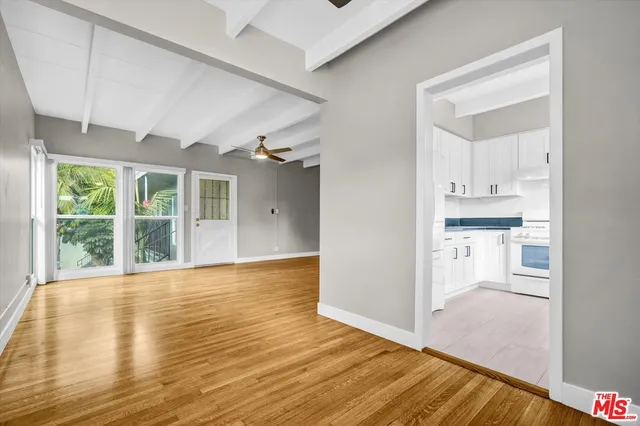 an empty room with wooden floor fan and windows