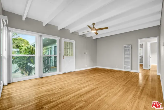 a view of an empty room with a window and wooden floor