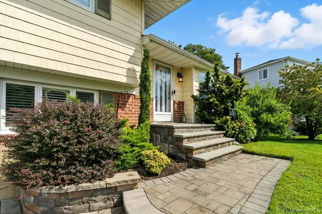 a view of a house with potted plants and a bench