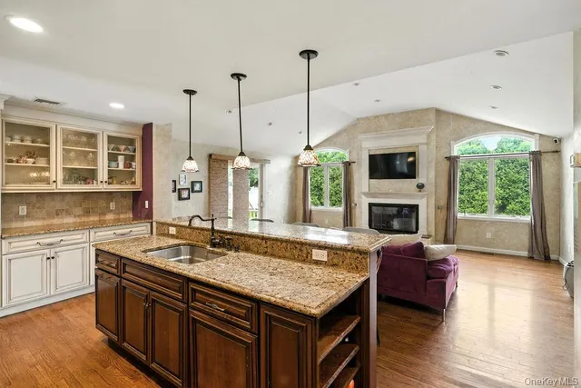 a kitchen with kitchen island granite countertop a stove a sink a center island and wooden floor