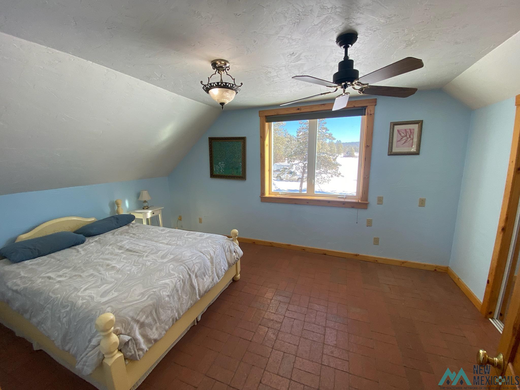 150 Forrest Service Road 124 Road Chamisal, NM 87521 - Photo 41 of 42 Bedroom featuring brick patterned flooring, lofted ceiling, a textured ceiling, and ceiling fan