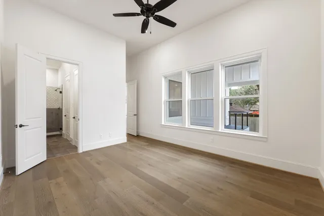 a view of an empty room with a window and wooden floor