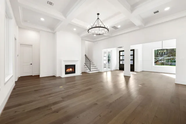 an empty room with wooden floor fireplace and windows