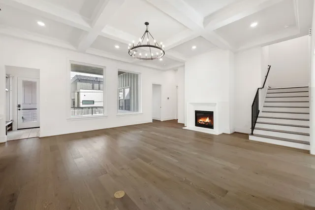 an empty room with wooden floor fireplace and windows