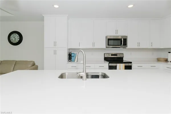 a kitchen with kitchen island a microwave a stove and white cabinets
