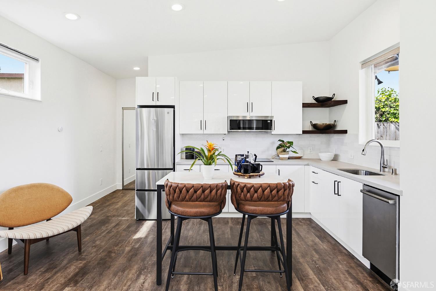 1610 Oregon Street Berkeley, CA 94703 - Photo 44 of 68 a kitchen with stainless steel appliances granite countertop a dining table chairs a refrigerator a sink a stove a microwave with wooden floor and cabinets