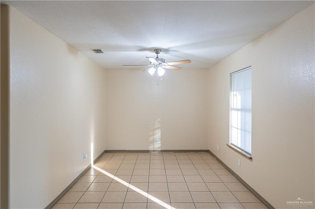 17002 Queen Palm Drive, Unit C Penitas, TX 78576 - Photo 6 of 10 Spare room featuring light tile patterned flooring, a ceiling fan, and a textured ceiling