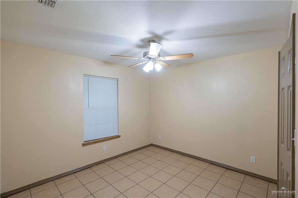 17002 Queen Palm Drive, Unit C Penitas, TX 78576 - Photo 8 of 10 Empty room featuring light tile patterned floors and ceiling fan