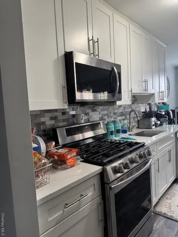 a kitchen with stainless steel appliances a stove a microwave a sink and cabinets