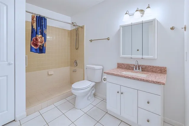a bathroom with a granite countertop sink mirror vanity and toilet