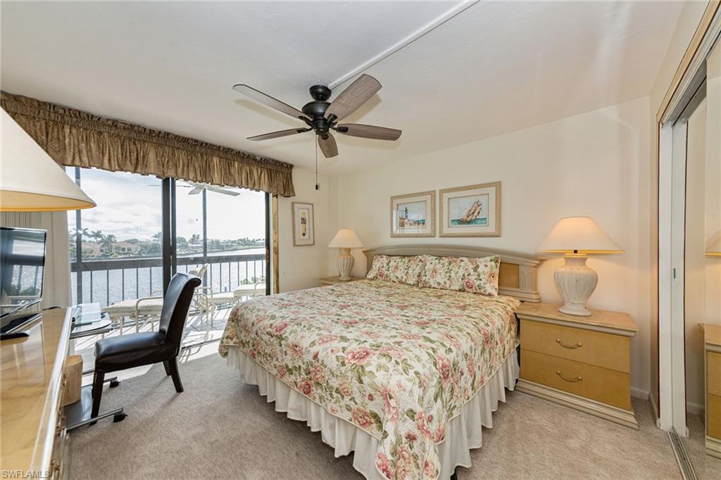 591 Seaview Court, Unit A306 Marco Island, FL 34145 - Photo 8 of 16 a bedroom with a bed and a chandelier