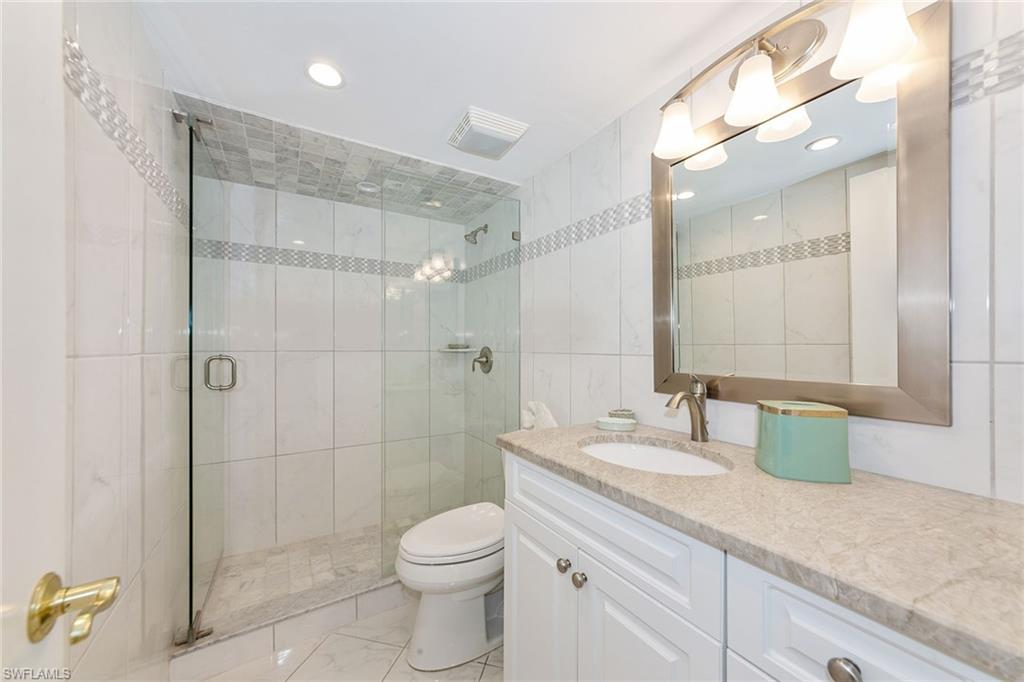 591 Seaview Court, Unit A306 Marco Island, FL 34145 - Photo 10 of 16 a bathroom with a granite countertop sink a toilet and shower