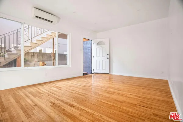 a view of an empty room with wooden floor and windows