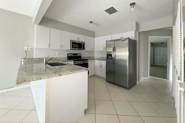 a kitchen with stainless steel appliances granite countertop a refrigerator a stove and a sink