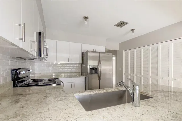 a kitchen with granite countertop a refrigerator and a sink