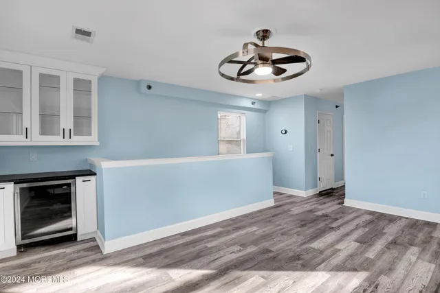 a view of an empty room with a kitchen and chandelier fan
