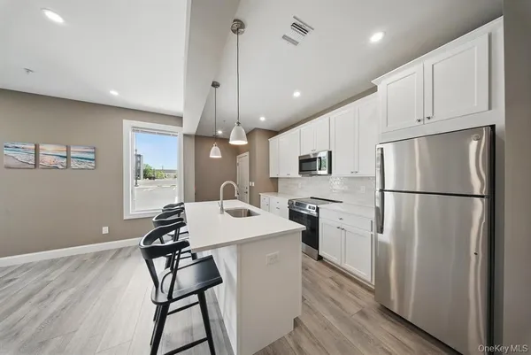 a kitchen with stainless steel appliances a refrigerator a stove a sink dishwasher a dining table and chairs with wooden floor