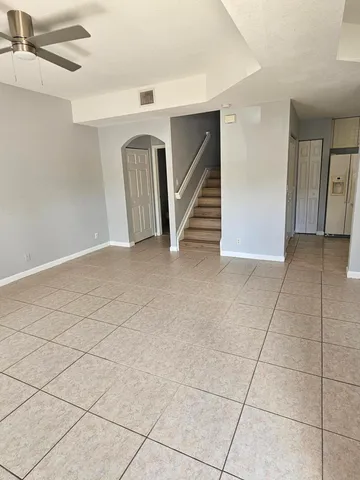 a view of an empty room with staircase and a kitchen view