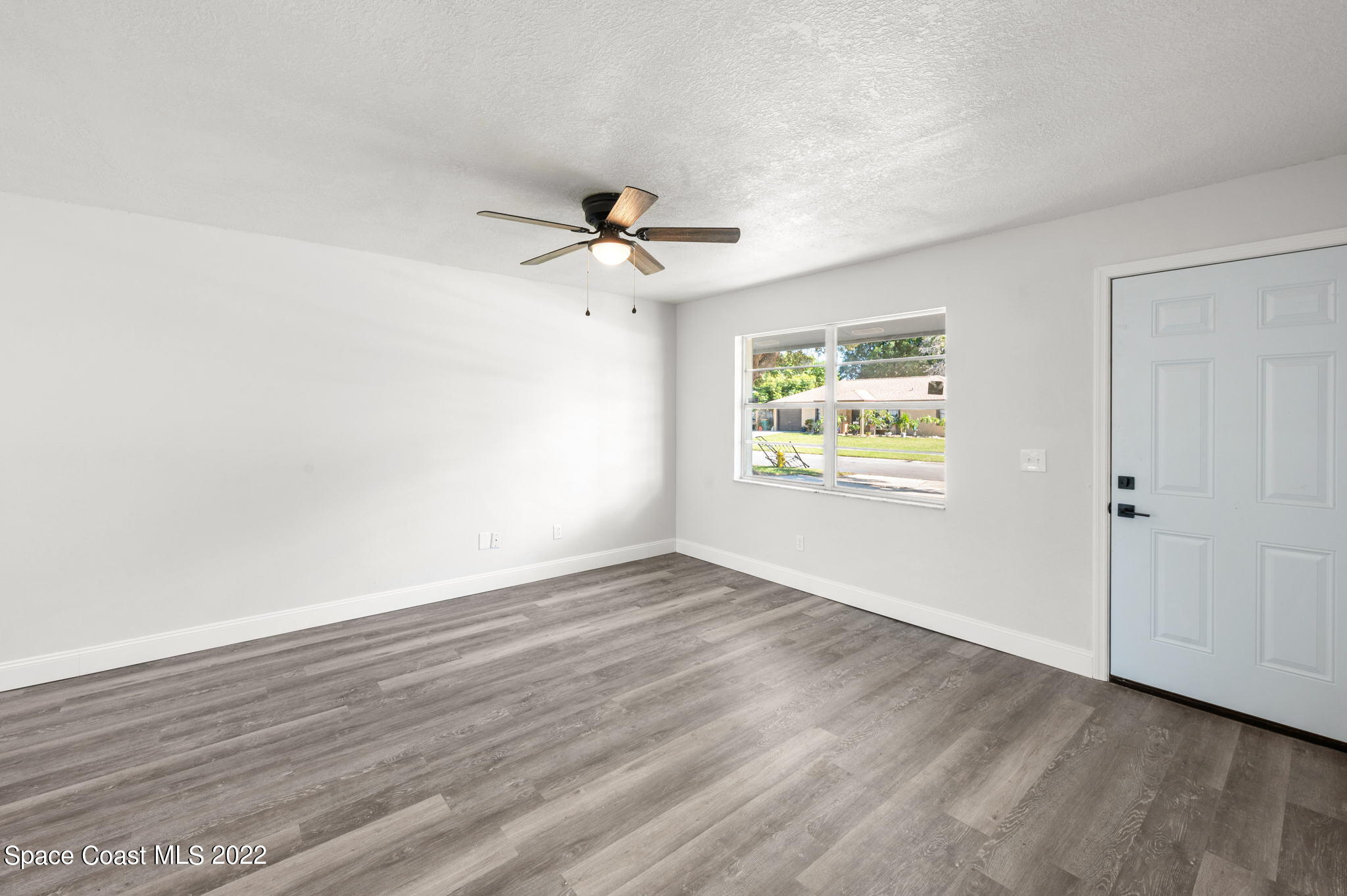 2856 Lancaster Road Melbourne, FL 32935 - Photo 3 of 22 an empty room with wooden floor ceiling fan and windows
