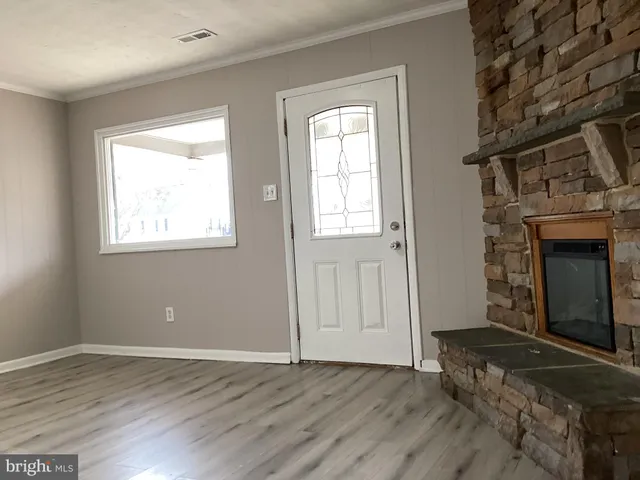 an empty room with wooden floor fireplace and windows
