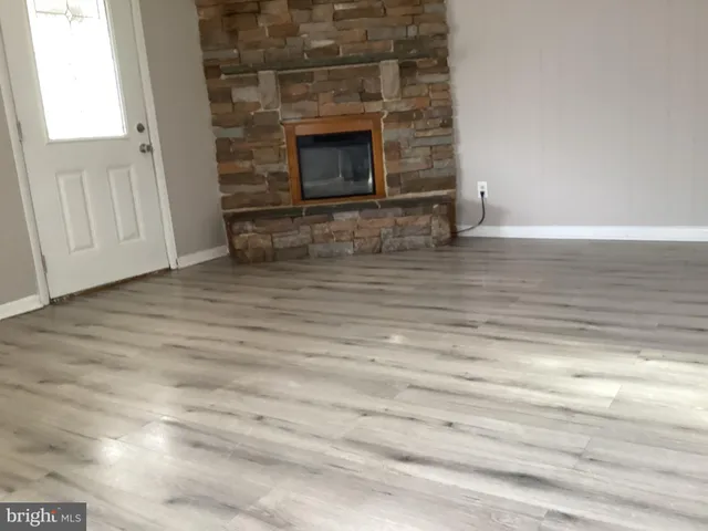 a view of empty room with wooden floor and fireplace