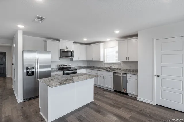 a large kitchen with cabinets stainless steel appliances and a counter top space