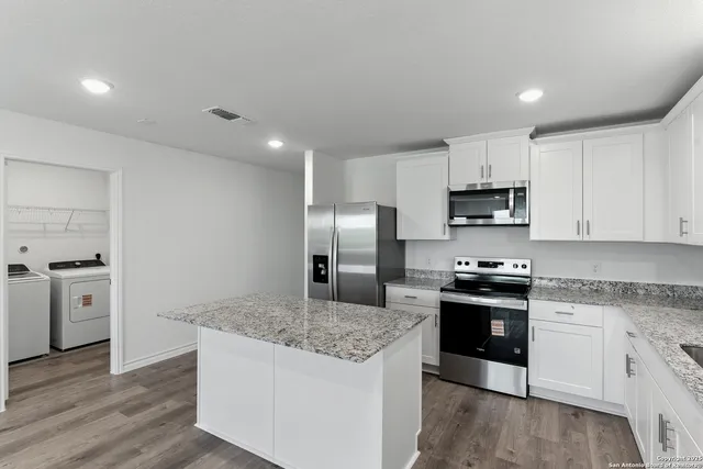 a kitchen with stainless steel appliances granite countertop a sink stove microwave and refrigerator