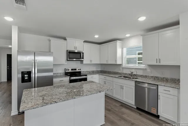 a kitchen with stainless steel appliances granite countertop a sink stove and refrigerator