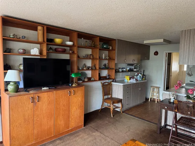 a living room with furniture a flat screen tv and kitchen view