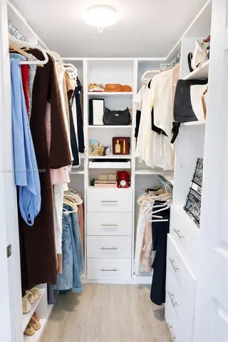 a view of walk in closet with clothes and shoes