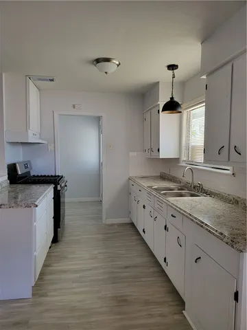 a large kitchen with granite countertop a stove and a sink