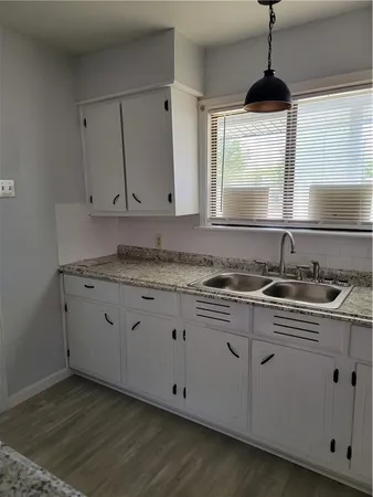 a kitchen with granite countertop white cabinets and a sink