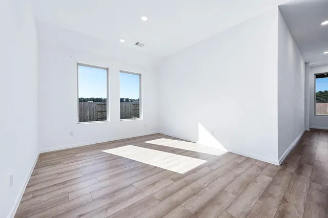 an empty room with wooden floor and windows