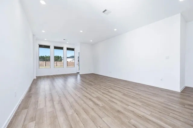 an empty room with windows and ceiling fan