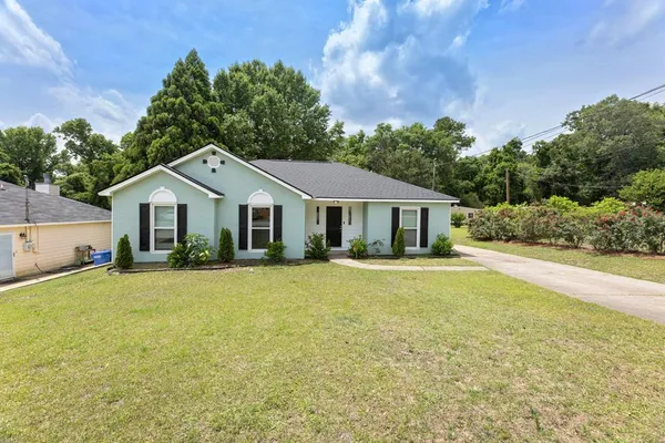 a front view of house with yard and trees in the background