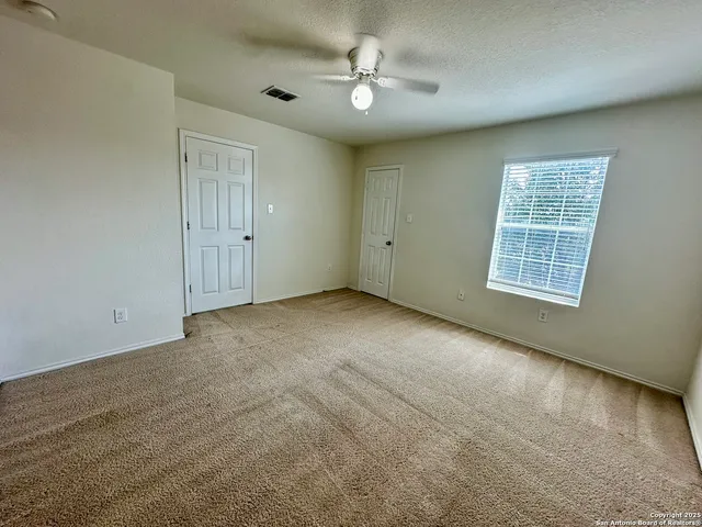 an empty room with windows and fan