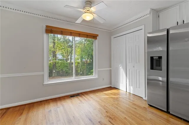 an empty room with wooden floor fan and windows
