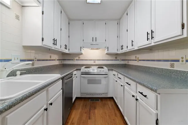 a kitchen with granite countertop white cabinets and white appliances