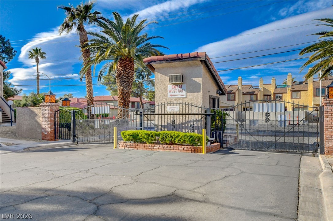 1751 East Reno Avenue, Unit 228 Las Vegas, NV 89119 - Photo 36 of 39 A secured community entry with iron gates, lush palm trees, and a functional guardhouse welcomes residents home.